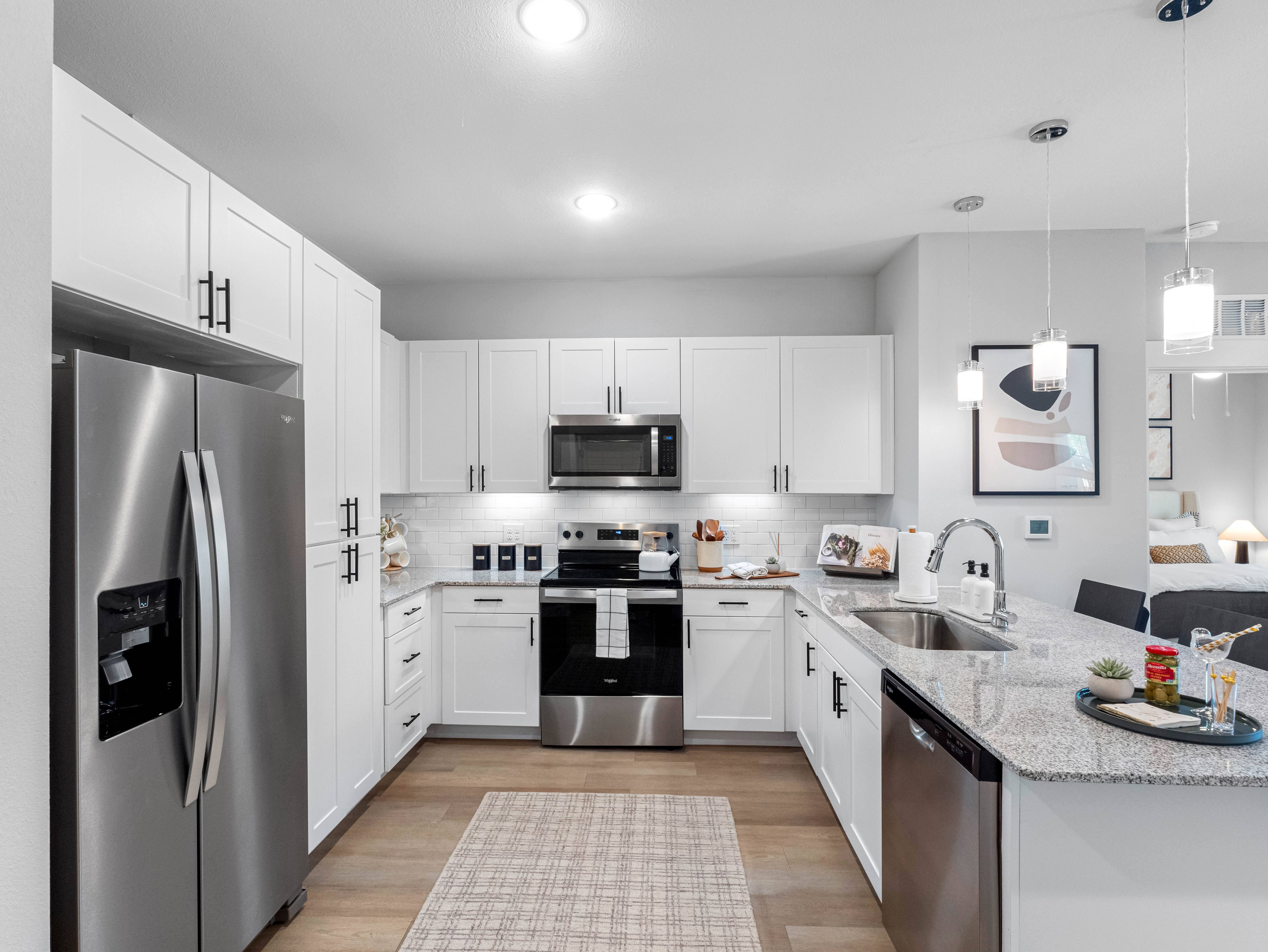 A modern kitchen with white cabinets and stainless steel appliances.